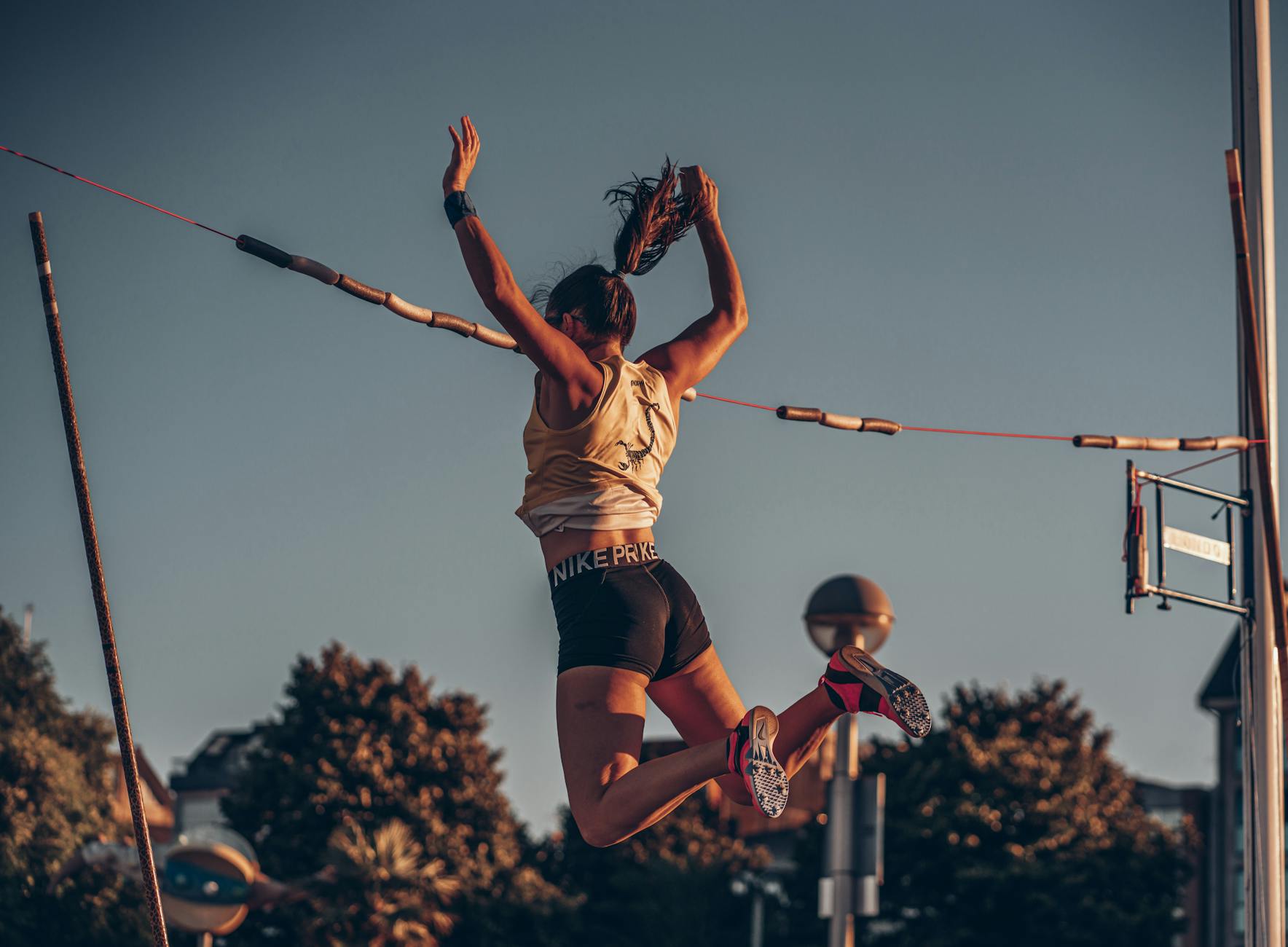 Zawodniczka w skoku wzwyż na stadionie o zachodzie słońca