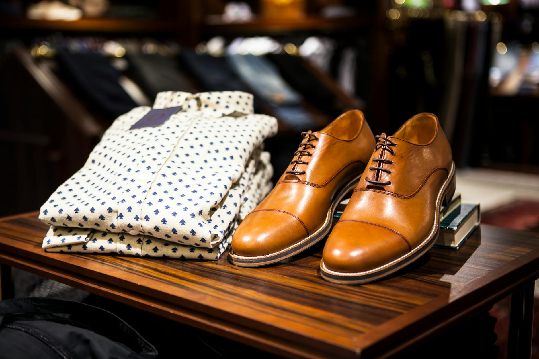 Brązowe eleganckie buty i koszula we wzory na drewnianym stole w butiku