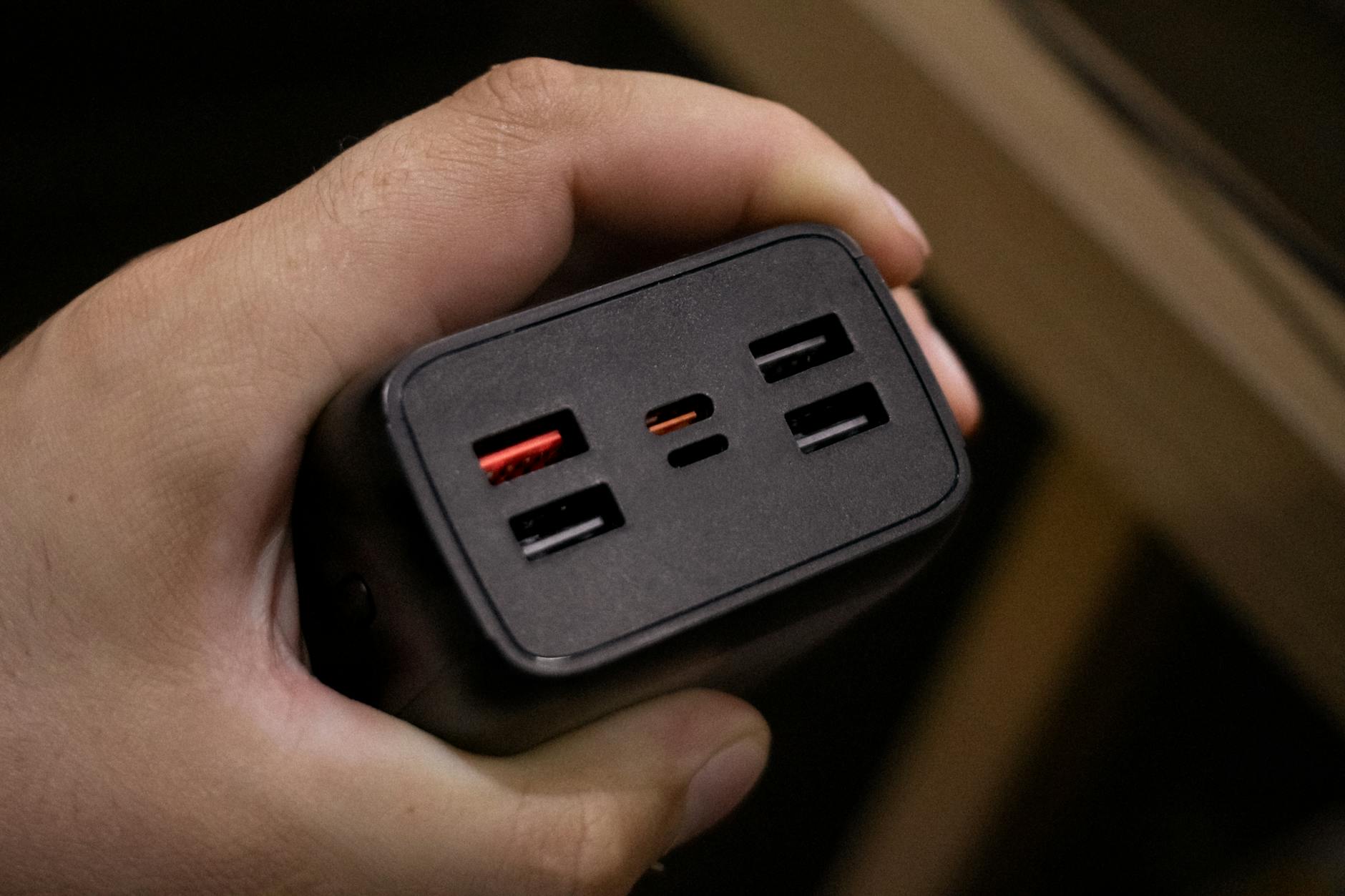 Dłoń trzymająca adapter z wieloma portami USB, zbliżenie na gniazda