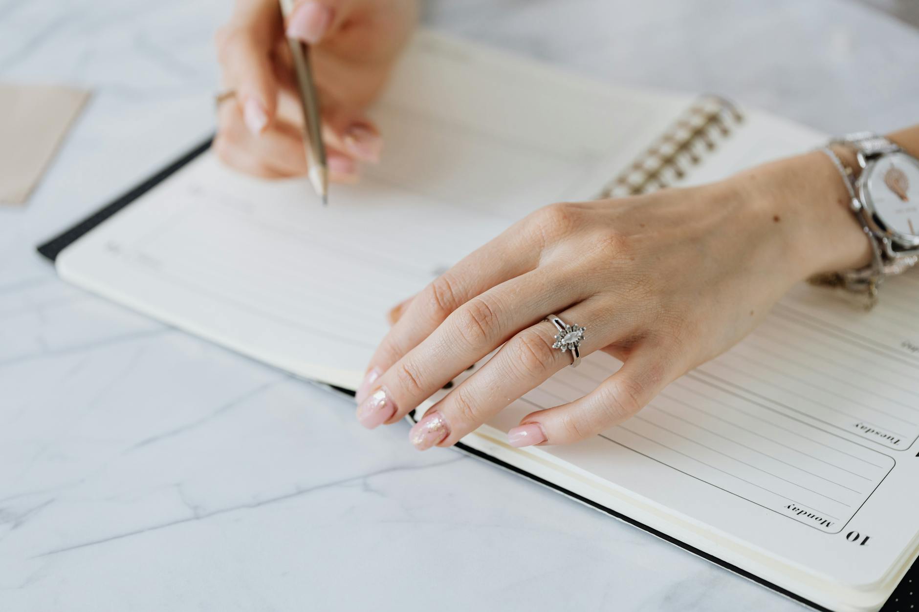 Dłonie zapisujące plan wesela w notesie