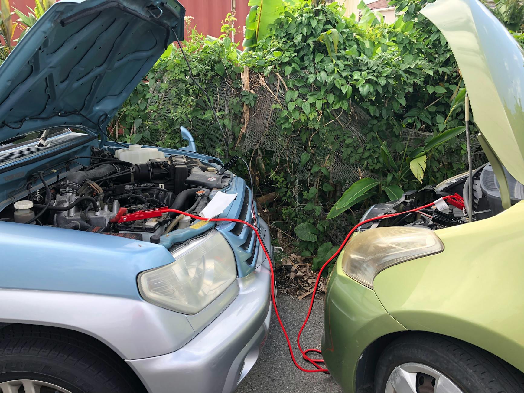 Dwa samochody połączone kablami rozruchowymi na parkingu