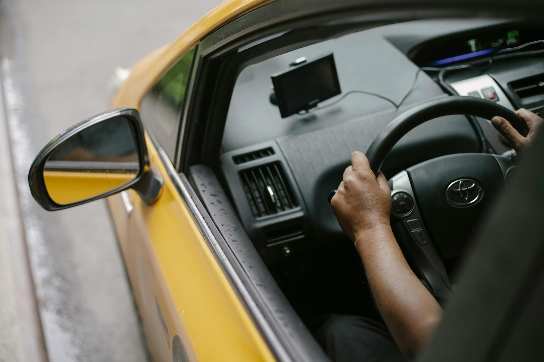 Kierowca prowadzi żółtą taksówkę z nawigacją GPS w ruchu miejskim