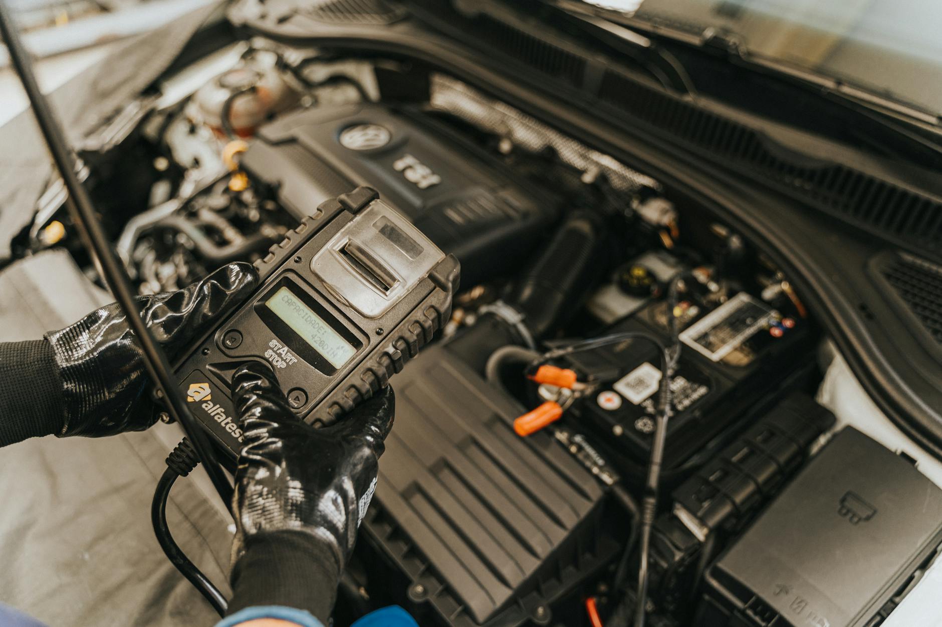Mechanik diagnozuje silnik auta testerem akumulatora po zimie