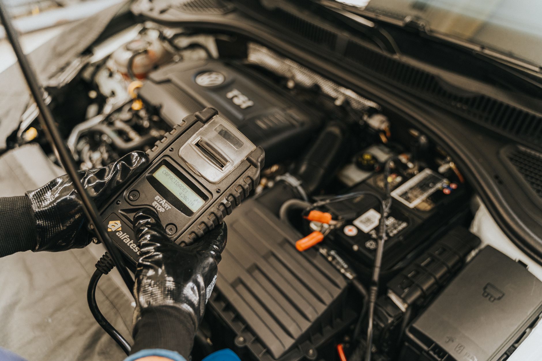 Mechanik diagnozuje silnik samochodu elektronicznym miernikiem